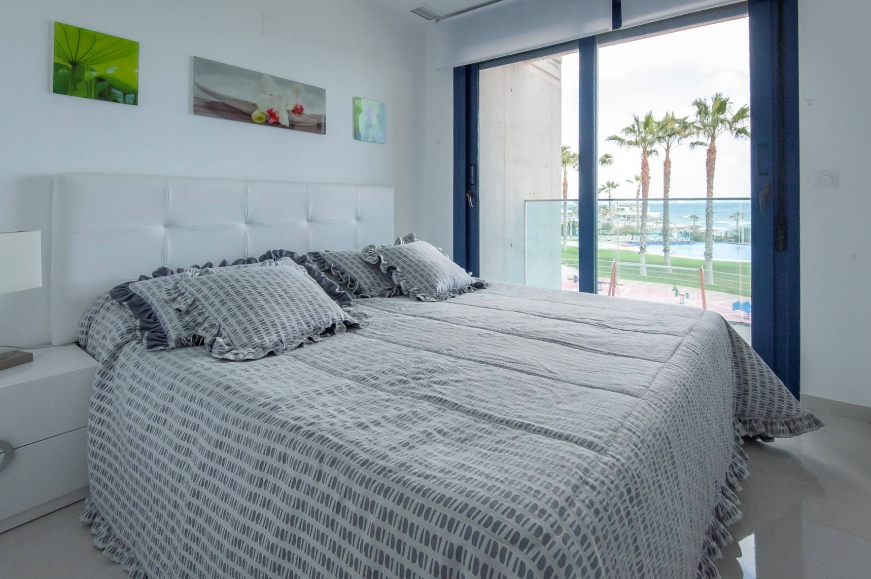 Et soverom med dobbeltseng og utsikt til en strand med palmer